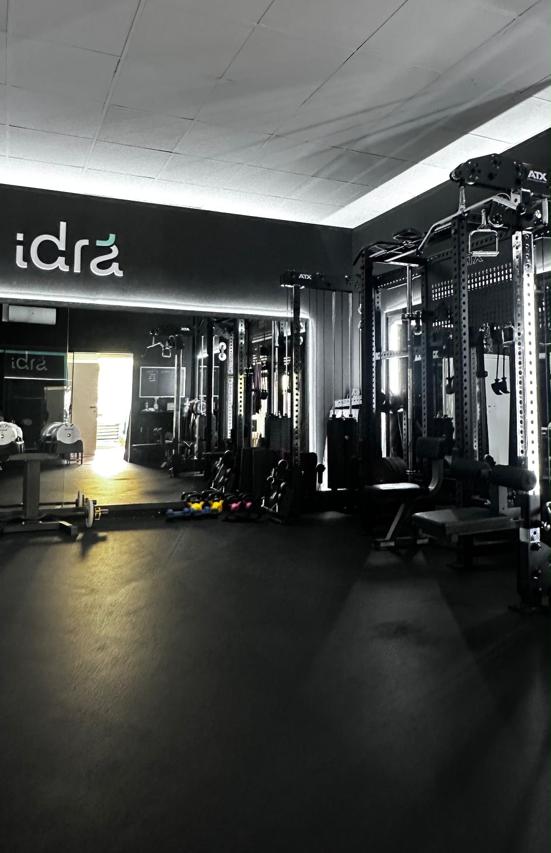 Rack ATX con stazione a cavi e panche davanti alla parete a specchio nello studio privato di personal training a Trento