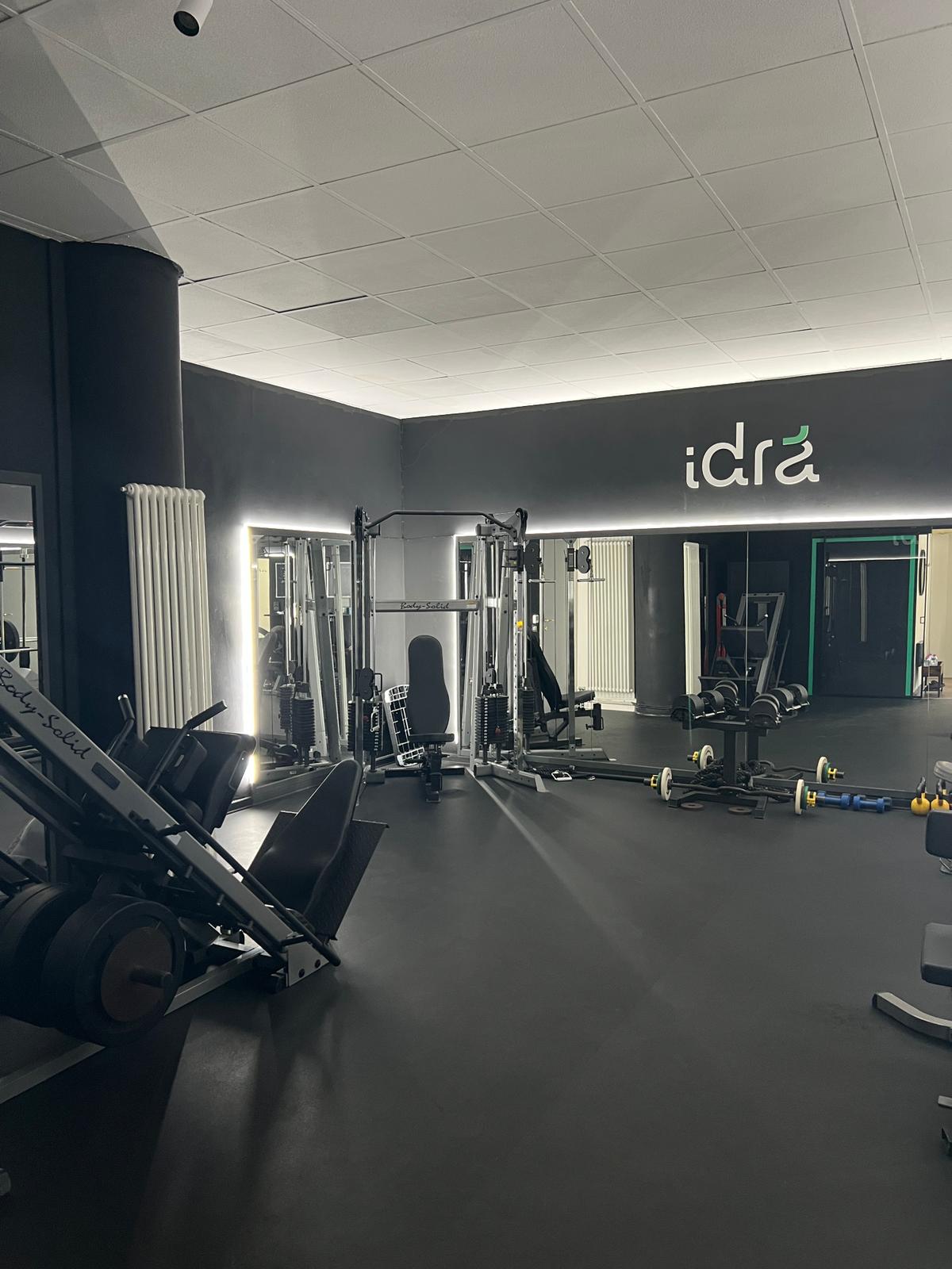Weight room with Body-Solid rack and backlit Idra logo in the private personal training studio in Trento